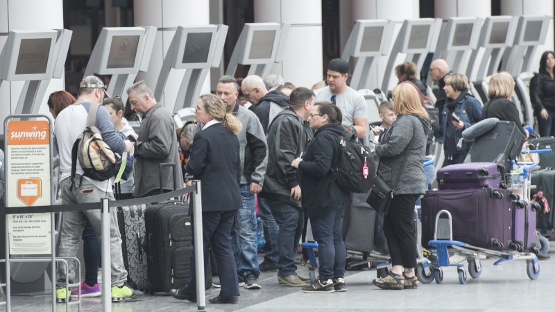 Passengers line up at a check in desk at Trudeau Airport in Montreal on March 13, 2019. THE CANADIAN PRESS/Graham Hughes
