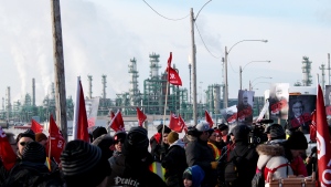 The Co-op Refinery Complex is seen behind a group of members of Unifor 594, picketing outside a gate. (Brendan Ellis/CTV News)