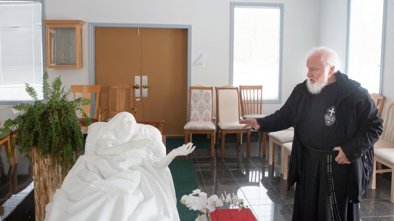 Father Claudio Piccinini, a Catholic priest and founder of "Teopoli, the City of God," a religious place of worship, in Gravenhurst, Ont., stands with a white Carrara marble monument of Sister Carmelina lying in her hospital bed, on Friday, December 13, 2019. (THE CANADIAN PRESS/Chris Young)