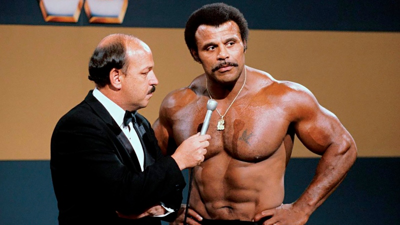 In this undated photo provided by WWE, Inc., 'Mean' Gene Okerlund interviews Rocky 'Soul Man' Johnson. Johnson, a WWE Hall of Fame wrestler who became better known as the father of actor Dwayne 'The Rock' Johnson, died Wednesday, Jan. 15, 2020. He was 75. (WWE, Inc. via AP)