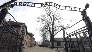 A man walks through the gate of the Sachsenhausen Nazi death camp with the phrase 'Arbeit macht frei' (work sets you free) at the International Holocaust Remembrance Day, in Oranienburg, about 30 kilometers, (18 miles) north of Berlin, Germany, Sunday, Jan. 27, 2019. (AP Photo/Markus Schreiber)