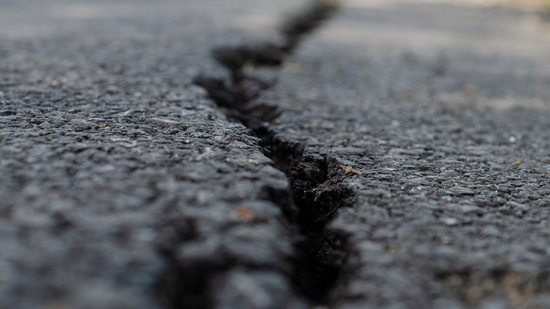 A cracked driveway is shown in an image from shutterstock.com