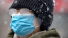 A woman's eyeglasses are fogged up as she wears a face mask during a snowfall in Beijing, Sunday, Feb. 2, 2020. (AP Photo/Mark Schiefelbein)