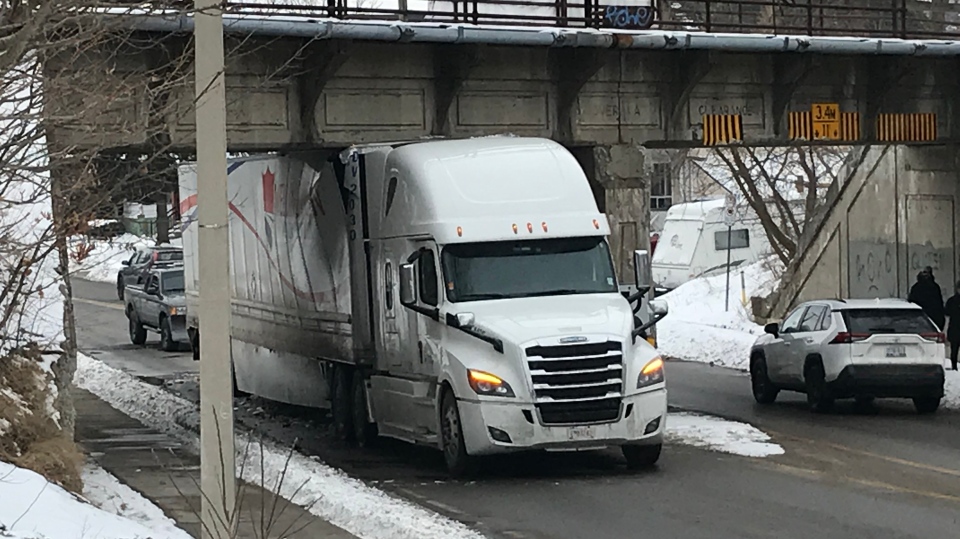 A truck wedged under a rail bridge