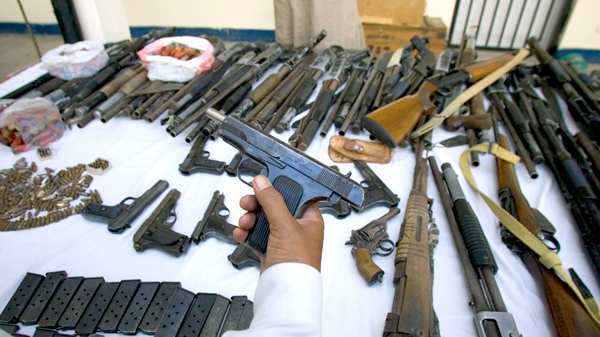 A Pakistani police officer shows a pistol and other confiscated weapons at a police station in Islamabad, Pakistan, on Saturday, Sept. 19, 2009. (AP / Anjum Naveed)