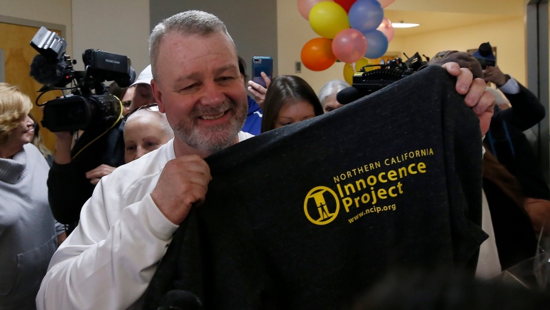Ricky Davis holds up a shirt with the logo of the Innocence Project after he was released from custody at the El Dorado County Jail in Placerville, Calif., Thursday, Feb. 13, 2020. (AP Photo/Rich Pedroncelli)