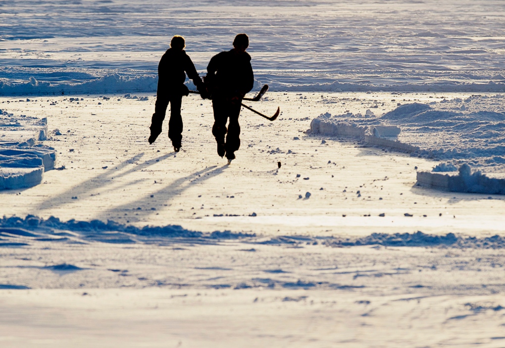 A pair of hockey players skating on a frozen lake