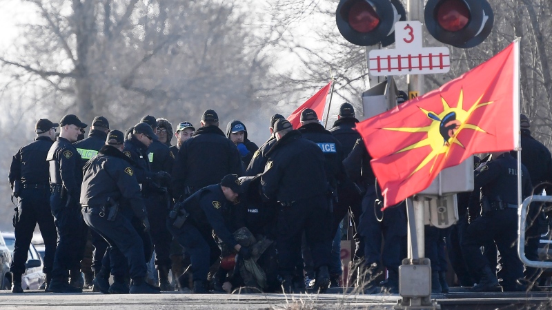 Ontario Provincial Police officers make an arrest at a rail blockade in Tyendinaga Mohawk Territory, near Belleville, Ont., on Monday Feb. 24, 2020. THE CANADIAN PRESS/Adrian Wyld