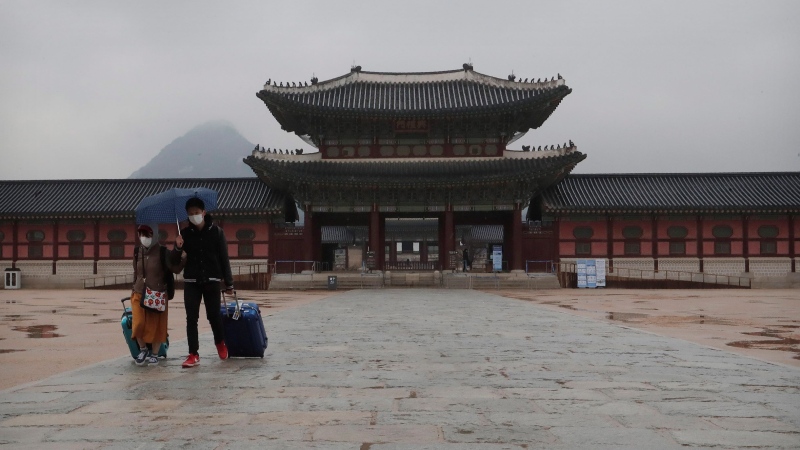 A couple wearing face masks visits the Gyeongbok Palace, the main royal palace during the Joseon Dynasty, in Seoul, South Korea, Friday, Feb. 28, 2020. Japan's schools prepared to close for almost a month and entertainers, topped by K-pop superstars BTS, canceled events as a virus epidemic extended its spread through Asia into Europe and on Friday, into sub-Saharan Africa. (AP Photo/Ahn Young-joon)