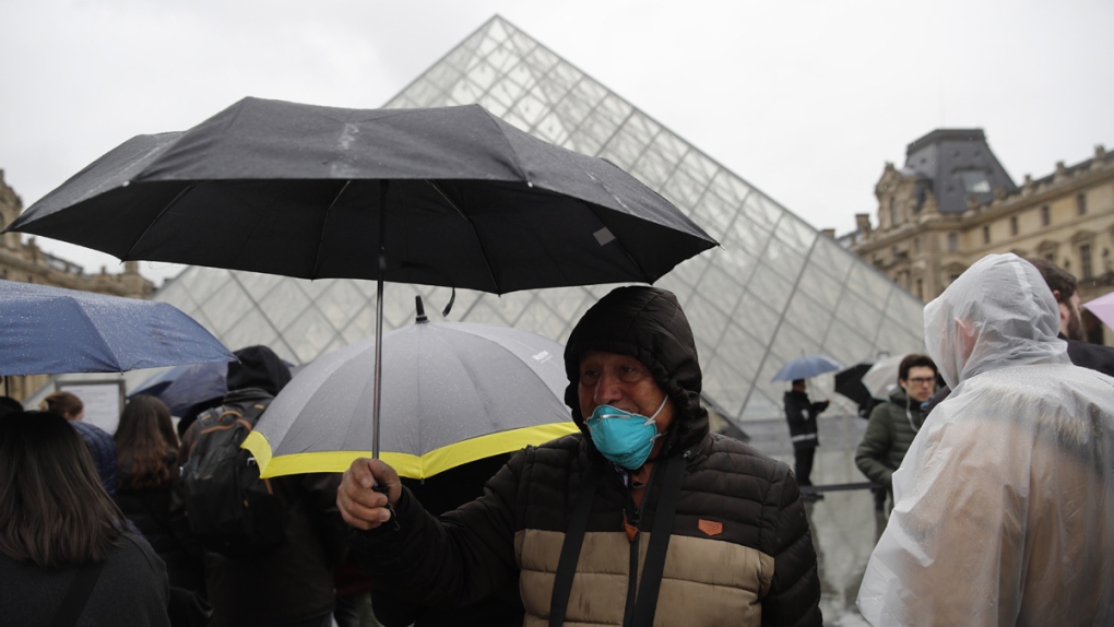 A tourist in a mask walks away from the Louvre