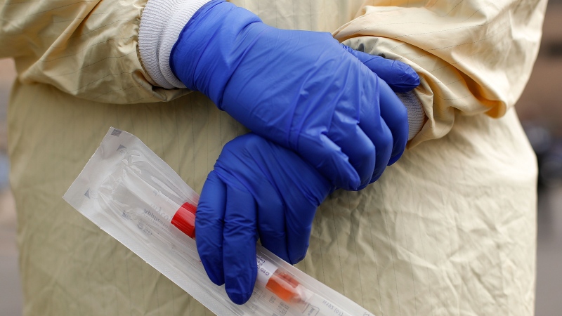 A nurse holds a swabs and test tube kit to test people for COVID-19, the disease that is caused by the new coronavirus, at a drive through station. (Paul Sancya/AP)
