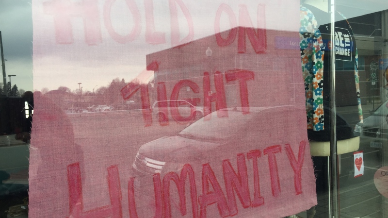 A sign reads 'Hold on Tight Humanity' in a storefront window in downtown Woodstock, Ont. on Thursday, March 26, 2020. (Bryan Bicknell / CTV London)