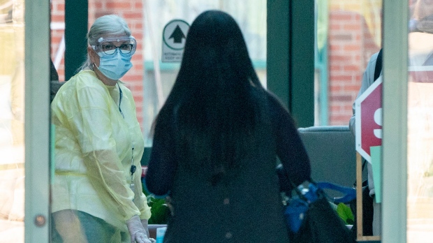 A nurse in protective gear greets a woman entering the Seven Oaks Long-Term Care Home in Toronto on Thursday, April 2, 2020. A number of residents at the home have died from COVID-19. THE CANADIAN PRESS/Frank Gunn