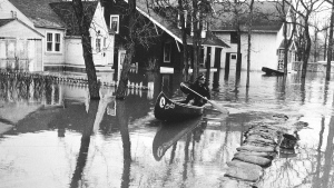 An image of man canoeing in a flooded residential area in 1950. (Source: Province of Manitoba)