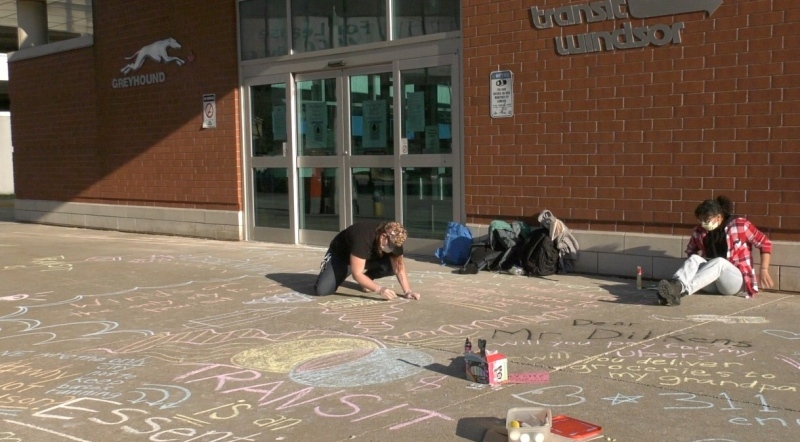 Protesters write messages in chalk on the sidewalk of the downtown Transit Windsor terminal on Friday, April 3, 2020 as the group calls for the suspension of the service to end. 
(Ricardo Veneza / CTV Windsor)