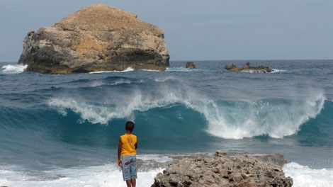 A youth watches the waves crash along the shores of Pointe-des-Chateaux as Tropical Storm Erika approaches the Caribbean island of Guadeloupe, Wednesday, Sept. 2, 2009. (AP Photo/Dominique Chomereau-Lamotte)
