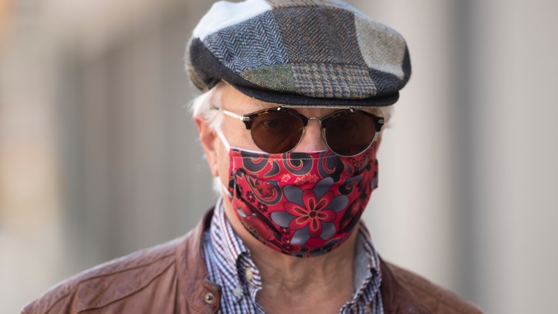 Paul Pedersen wears a mask quilted by his wife as he walks along the street in Ottawa, Monday April 6, 2020. (Adrian Wyld/THE CANADIAN PRESS)