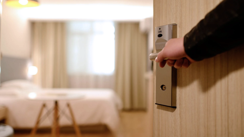 A man opens the door to a hotel room. 
