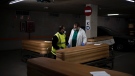 In this April 14, 2020, photo, head mortician Jordi Fernandez, right, speaks to a colleague after closing the coffin of a COVID-19 victim in an underground parking garage turned into a morgue at the Collserola funeral home in Barcelona, Spain.(AP Photo/Felipe Dana)