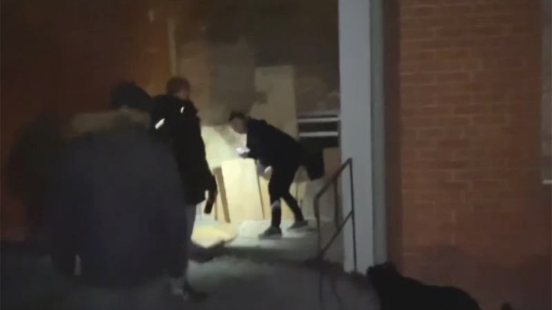 This image taken from YouTube video appears to show people removing boards from windows at the old London Psychiatric Hospital in London, Ont. (Andrew Cross / YouTube)