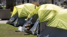 A homeless person lies in a tent pitched in a centre reservation in downtown in Toronto on Saturday, April 18, 2020. (THE CANADIAN PRESS / Chris Young)