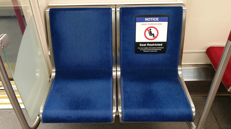 A sign restricting access to a seat on a subway train in order to promote physical distancing is shown.