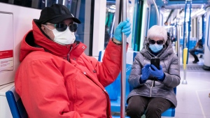 A couple wearing a protective masks ride a near empty subway train in Montreal, on Wednesday, April 22, 2020. THE CANADIAN PRESS/Paul Chiasson