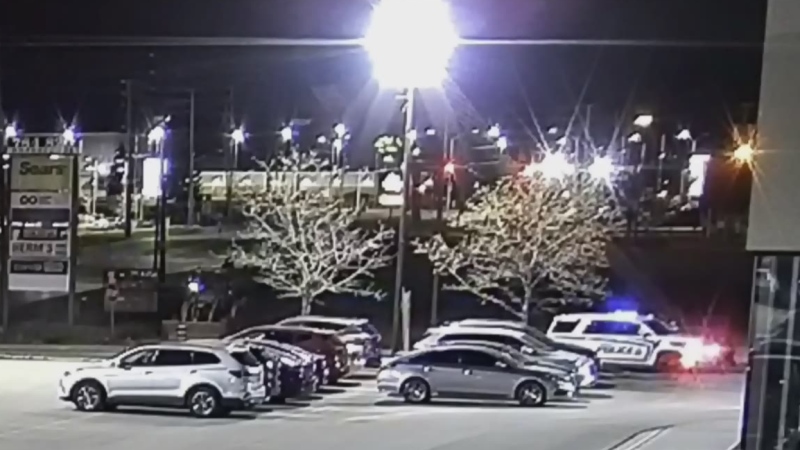 A police cruiser pulls into the parking lot of a high-end car dealership in London, Ont. in this image taken from surveillance video.