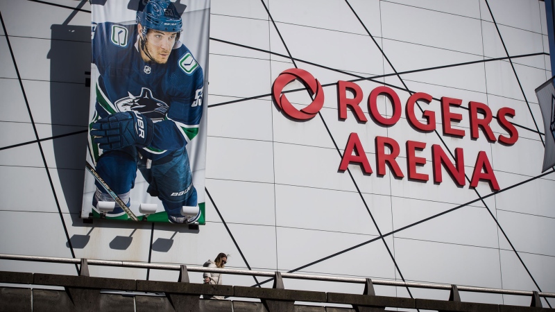 A woman walks past a large photo of Vancouver Canucks captain Bo Horvat outside Rogers Arena, home to the NHL team, in Vancouver, on Thursday, March 12, 2020. THE CANADIAN PRESS/Darryl Dyck