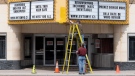 Two men work on the marquee of an independent theatre in Ottawa, Wednesday, May 6, 2020. (Adrian Wyld/THE CANADIAN PRESS)