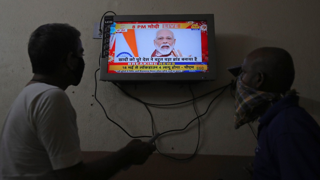 Indians watch a televised address by PM Modi
