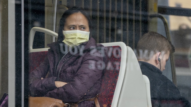 A woman wears a mask as she rides a TTC streetcar in Toronto on Friday, March 20, 2020. The gradual reopening of Canada's economy will not mean business as usual for the country's public transit agencies. THE CANADIAN PRESS/Frank Gunn