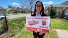 Sacred Heart vice principal Mary Jane Gillier-Symes with a lawn sign for graduating students. Stittsville, ON. May 13, 2020. (Tyler Fleming / CTV News)