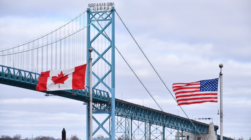 Canadian and American flags fly near the Ambassador Bridge at the Canada-USA border crossing in Windsor, Ont. on Saturday, March 21, 2020. (THE CANADIAN PRESS/Rob Gurdebeke)