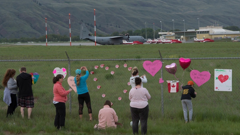 Canadian Forces Snowbirds planes are seen in the background as people place hearts and signs on the fence surrounding the airport in Kamloops, B.C., Sunday, May 17, 2020. THE CANADIAN PRESS/Jonathan Hayward