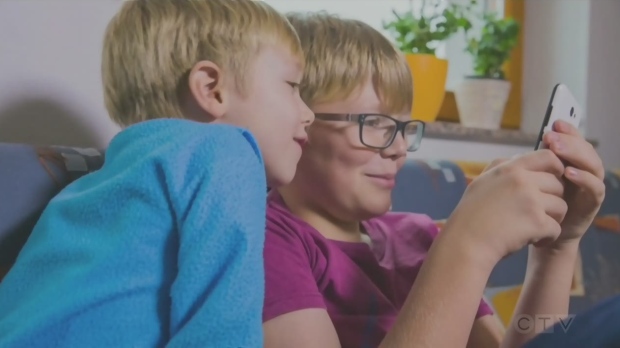 Two kids look at a smartphone