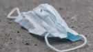 A discarded face mask is shown on a street next to a mobile COVID-19 testing clinic in Montreal, Sunday, May 17, 2020, as the COVID-19 pandemic continues in Canada and around the world. THE CANADIAN PRESS/Graham Hughes