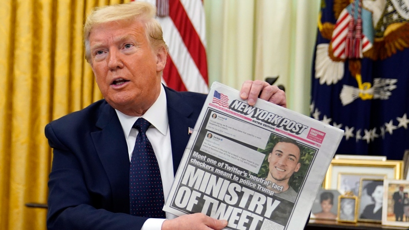 U.S. President Donald Trump holds up a copy of the New York Post as speaks before signing an executive order aimed at curbing protections for social media giants, in the Oval Office of the White House, Thursday, May 28, 2020, in Washington. (AP Photo/Evan Vucci)