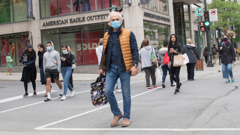 People with face masks and without face masks walk along Sainte-Catherine street in Montreal, Sunday, May 31, 2020, as the COVID-19 pandemic continues in Canada and around the world. THE CANADIAN PRESS/Graham Hughes