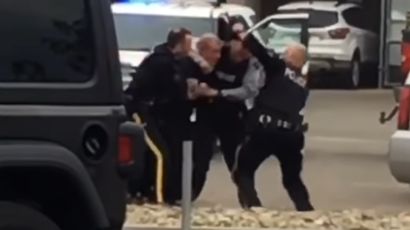 Three Kelowna RCMP officers attempt to take a man into custody in a parking lot on May 30, 2020. (Castanet.net) 