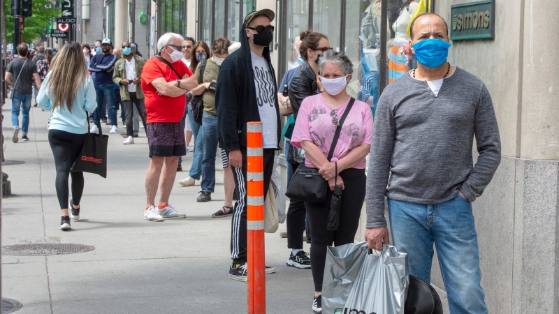 Masked customers line up outside a store in Montreal in this May 2020 file image. (THE CANADIAN PRESS / Ryan Remiorz)