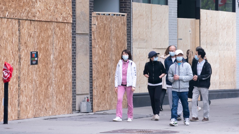 Shoppers walk past boarded up stores on Montreal's Sainte-Catherine street on Wednesday, June 3, 2020. (THE CANADIAN PRESS / Paul Chiasson)