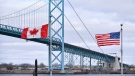 Canadian and American flags fly near the Ambassador Bridge at the Canada-USA border crossing in Windsor, Ont. on Saturday, March 21, 2020. Unique challenges are facing residents in Canadian and U.S. border cities and towns amid a ban on non-essential travel between the two countries during the pandemic. THE CANADIAN PRESS/Rob Gurdebeke