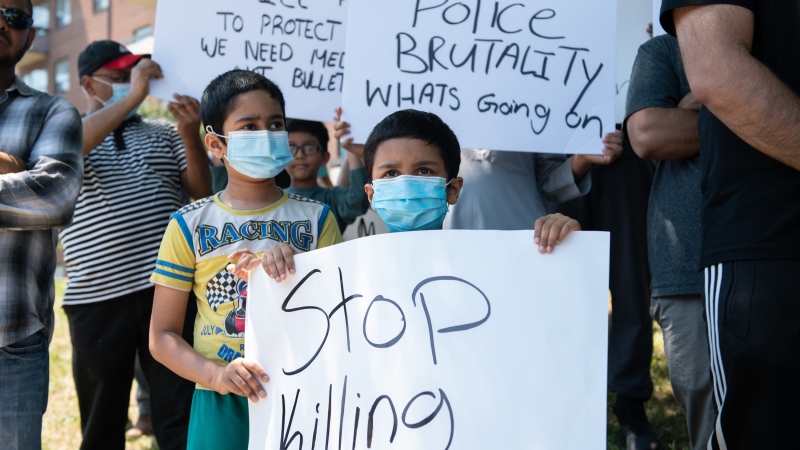 Children hold signs in front of the apartment building where Ejaz Choudry, a 62-year-old man who family members said was experiencing a schizophrenic episode, was shot by Peel Police and died at the scene the previous night, in Mississauga, Ont., Sunday, June 21, 2020. THE CANADIAN PRESS/Galit Rodan