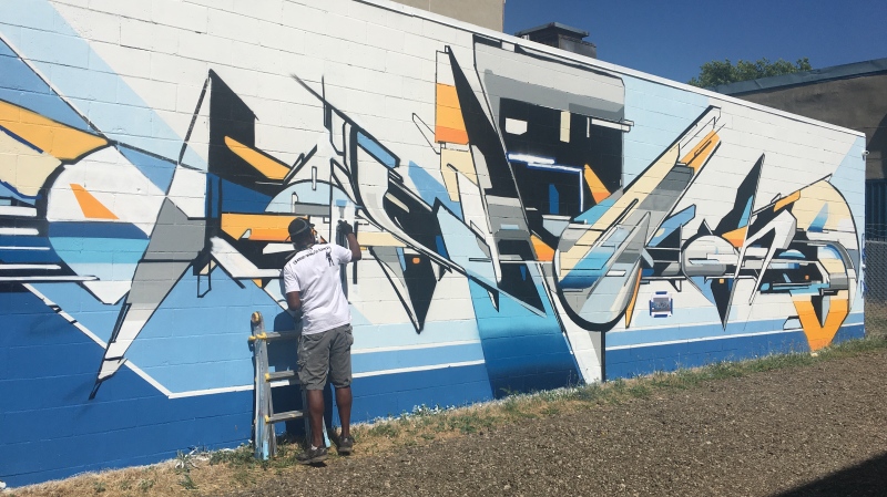 Evond 'Mediah' Blake works on a mural on Talbot Street in St Thomas, Ont. on Tuesday, June 30, 2020. (Brent Lale / CTV News)
