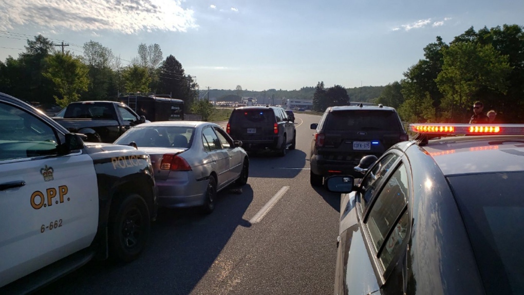 Police vehicles surround a silver car on a highway