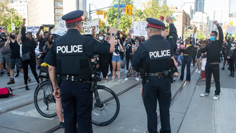 Police officers look on as protesters march in an anti-racism rally in Toronto on Saturday, June 6, 2020. (THE CANADIAN PRESS/Chris Young)