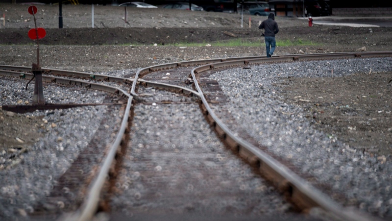 A man walks down the tracks in downtown of Lac-Megantic, Que Tuesday, June 10, 2014, where an oil-filled train screeched off the tracks and exploded killing 47 people. (THE CANADIAN PRESS/Paul Chiasson)