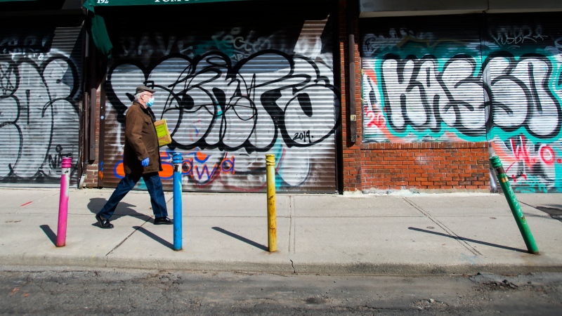 A lone person walks the empty streets in Kensington Market in Toronto on Wednesday, April 15, 2020. THE CANADIAN PRESS/Nathan Denette