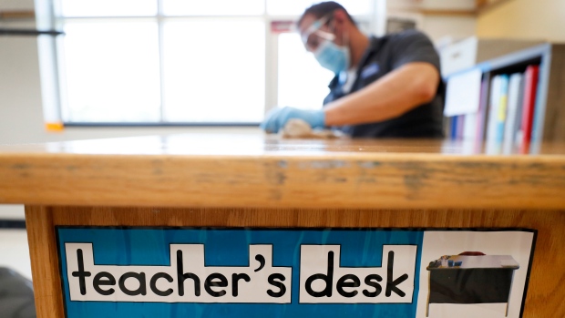 A custodian cleans a teacher's desk in a classroom at Brubaker Elementary School, Wednesday, July 8, 2020, in Des Moines, Iowa. (AP Photo/Charlie Neibergall)